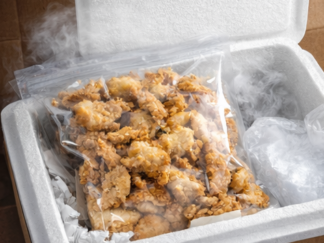 Sealed bag of fried whole belly clams in an insulated shipping box with dry ice